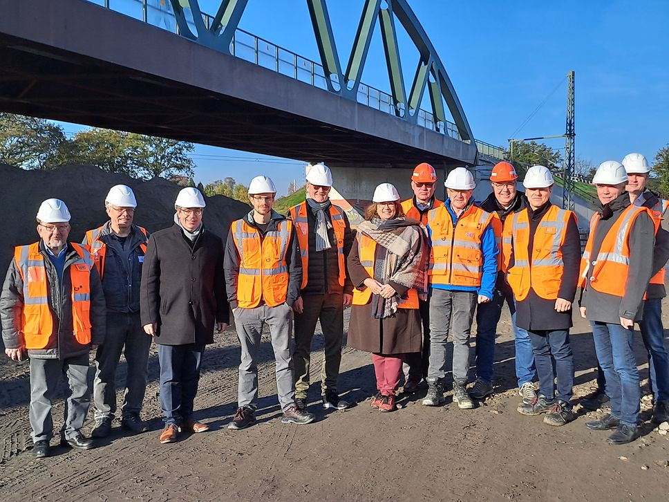 Eine Gruppe von Menschen mit Bauhelmen vor einer Brücke