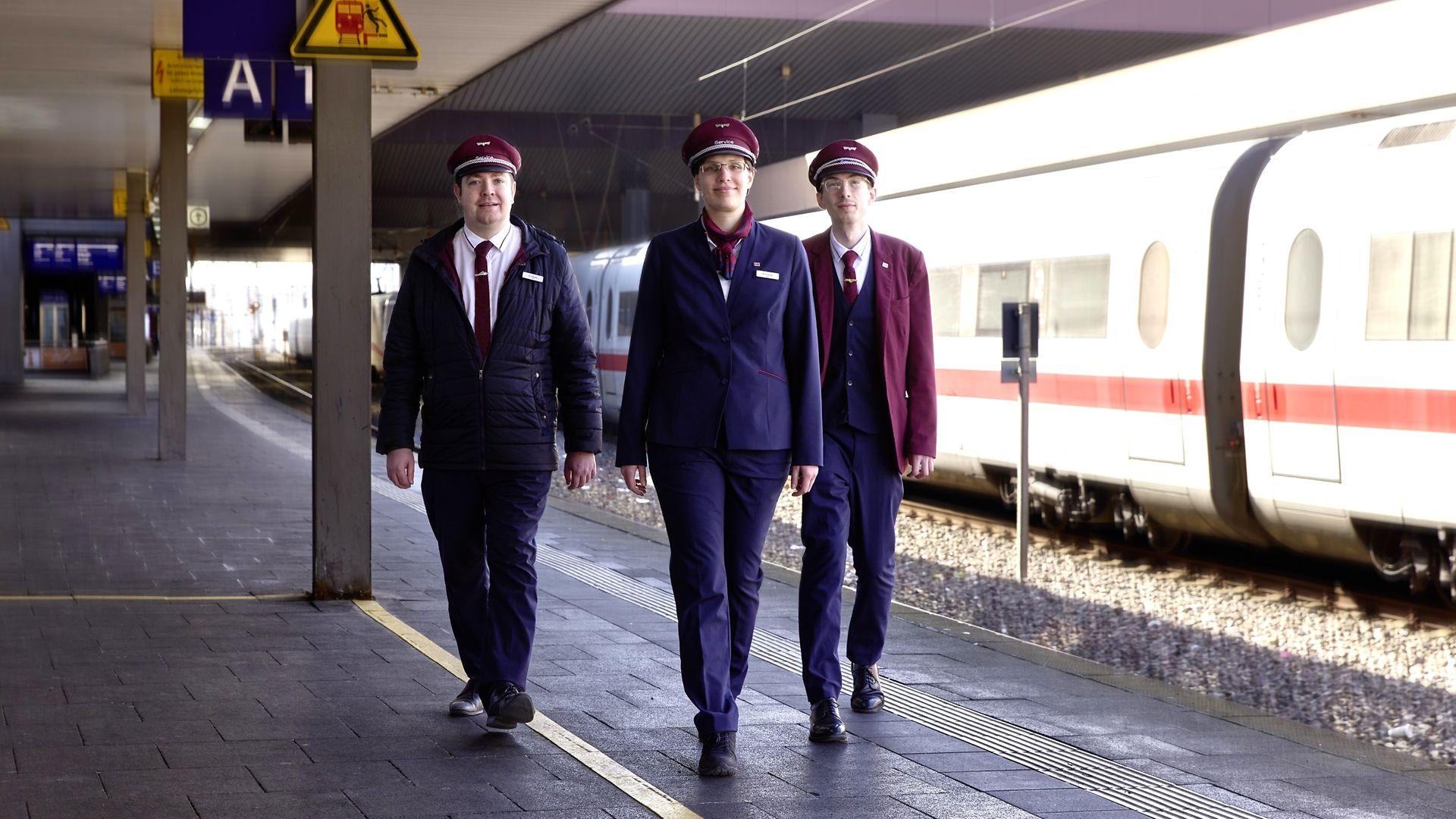 Marcel Czubin, Regina Schreiber und Nick Schulze von DB InfraGO laufen auf einem Bahnsteig vor einem ICE
