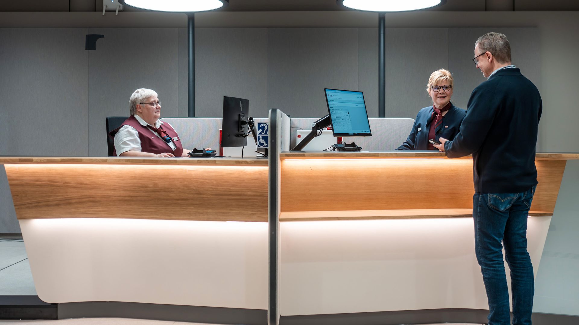 Zwei DB-Mitarbeiterinnen im Gespräch mit einem Kunden am Schalter