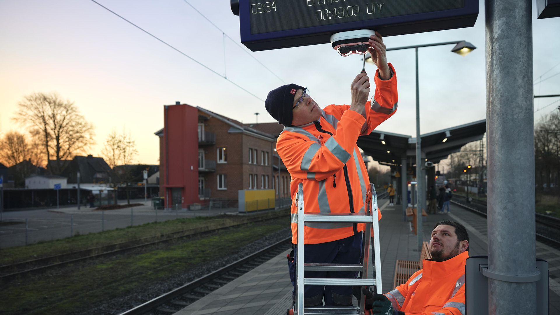 DB-Mitarbeiter reparieren Leuchten am Bahnsteig