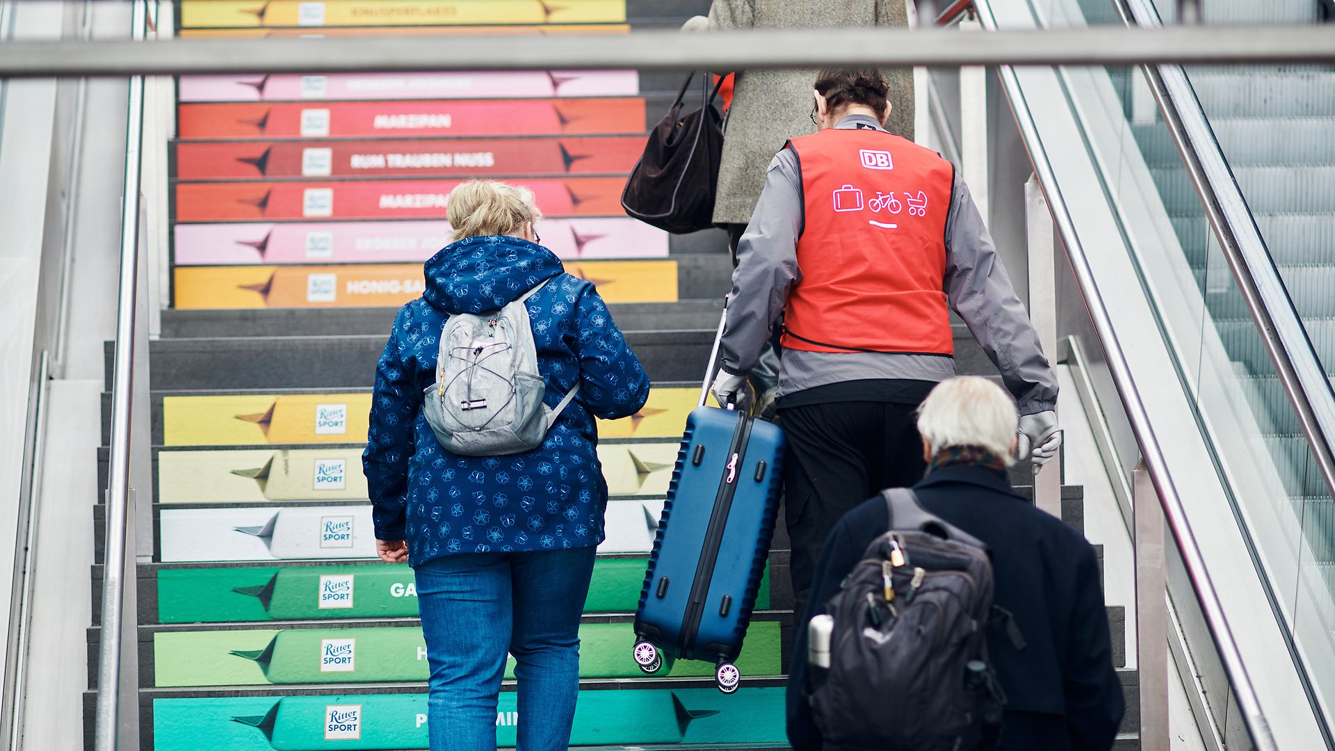 DB-Kofferträger auf einer Treppe in Regenbogenfarben