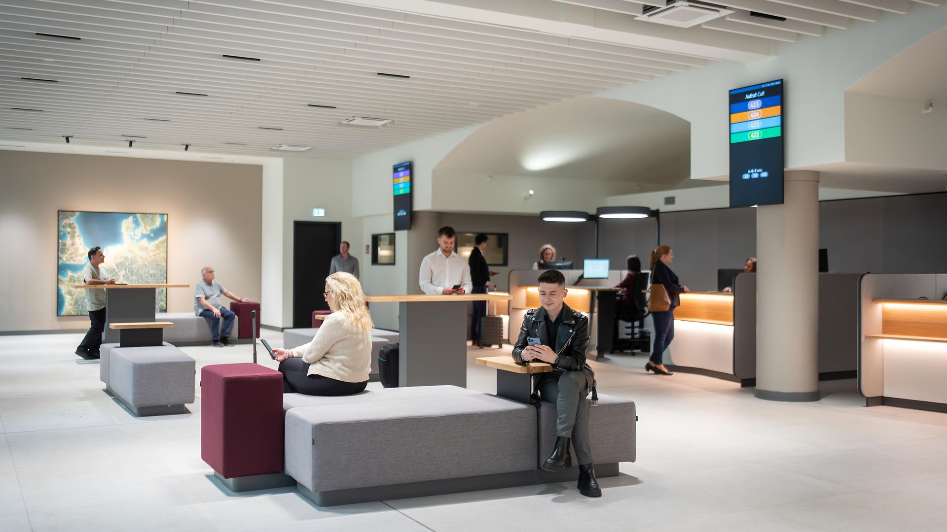 Sitzende Kund:innen im Wartebereich des Reisezentrums 