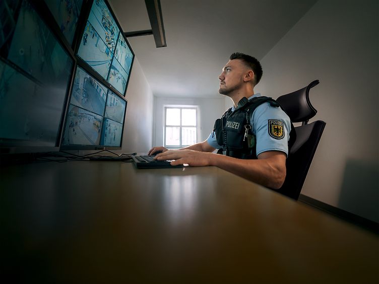 Polizist schaut auf den Monitor der Überwachungskameras